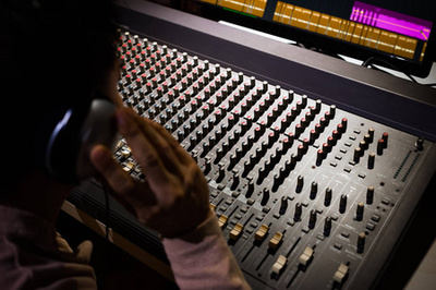 錄音室里坐著帶耳機的聲音制作人的剪裁鏡頭